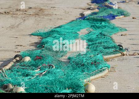 Eine Nahaufnahme bunter Fischernetze am Strand unter der Sonne Stockfoto