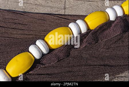 Eine Nahaufnahme bunter Fischernetze am Strand unter der Sonne Stockfoto