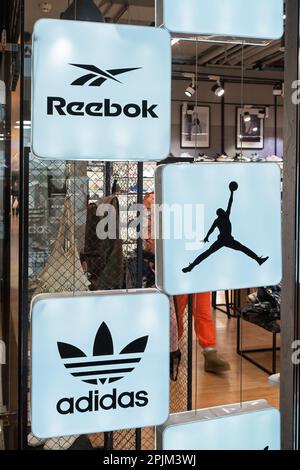 Reebok-, Air Jordan- und Adidas-Logos beliebter Schuh- und Bekleidungsmarken im Innenraum eines Sportgeschäfts mit mehreren Marken. Minsk, Belarus, 2023 Stockfoto