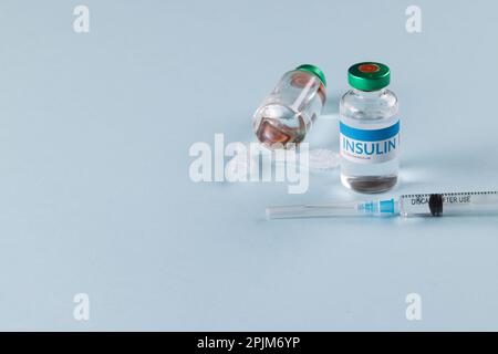 Durchstechflaschen mit Insulin mit Kapseln und Spritze auf blauem Hintergrund mit Kopierbereich Stockfoto