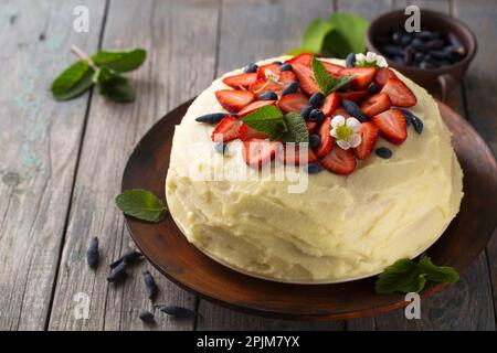 Hausgemachter Kuchen mit Vanille, Erdbeeren und Geißblatt auf rustikalem Hintergrund Stockfoto