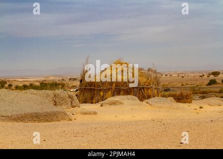 Tuareg-Lager in der Wüste. Runde Hütte, auf traditionelle Weise gebaut. Sahara Wüste, Algerien, Afrika Stockfoto