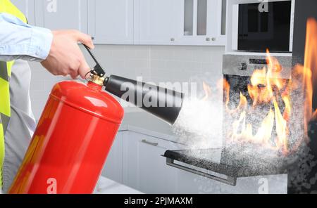 Ein Mann, der einen brennenden Ofen mit Feuerlöscher in der Küche ausstellt, schließt Stockfoto