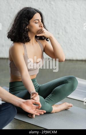 Eine Frau aus dem Nahen Osten in Sportbekleidung, die Gyan Mudra und Nasenloch praktiziert und im Yoga-Studio atmet, Stock Image Stockfoto