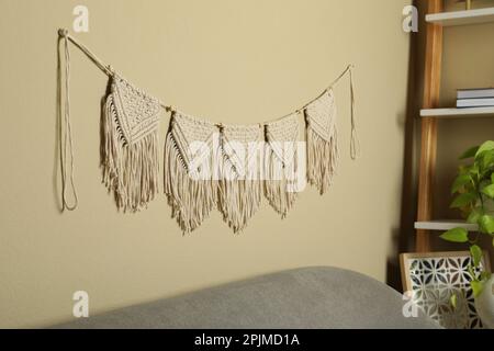 Wunderschöne große Makrame hängt an der beigen Wand im Wohnzimmer. Dekoratives Element Stockfoto