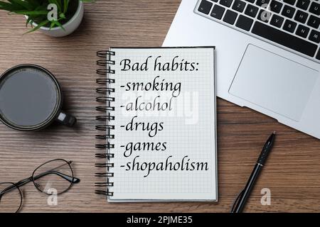 Notizbuch mit Liste der schlechten Gewohnheiten auf Holztisch, flach liegend Stockfoto