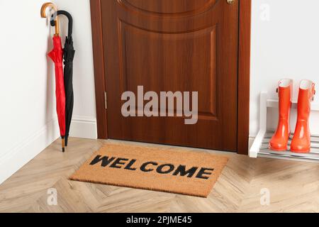 Türmatte mit Wort Willkommen auf Holzboden im Flur Stockfoto