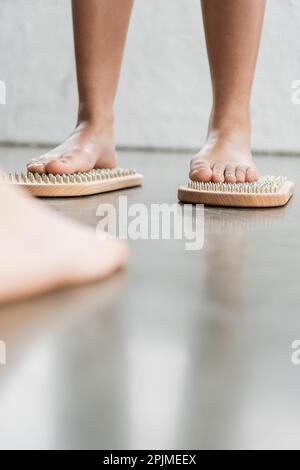 Verkürzter Blick auf eine barfuß Frau mit einem Tattoo, das auf einem Sadhu-Nagelbrett im Yoga-Studio steht, Stockbild Stockfoto
