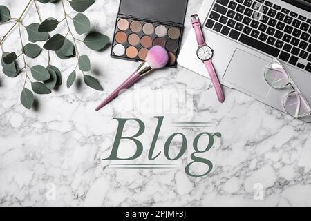 Arbeitsplatz des Bloggers mit Laptop und Make-up-Produkten auf weißem Marmorhintergrund, flach liegend Stockfoto