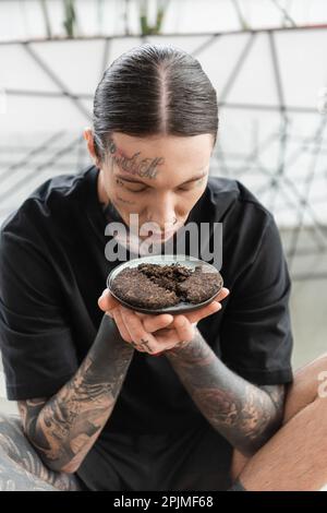 Junger Mann mit Tattoos, die fermentierte Teeblätter von Puer riechen, im Yoga-Studio, Stock Image Stockfoto
