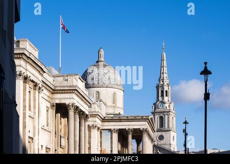 Eine Union-Jack-Flagge, die über der National Gallery mit dem Turm von St. Martin-in-the-Fields im Hintergrund. Die Nationalgalerie, Trafalgar Square Stockfoto