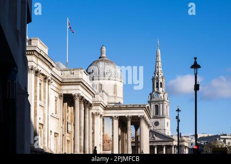 Eine Union-Jack-Flagge, die über der National Gallery mit dem Turm von St. Martin-in-the-Fields im Hintergrund. Die Nationalgalerie, Trafalgar Square Stockfoto