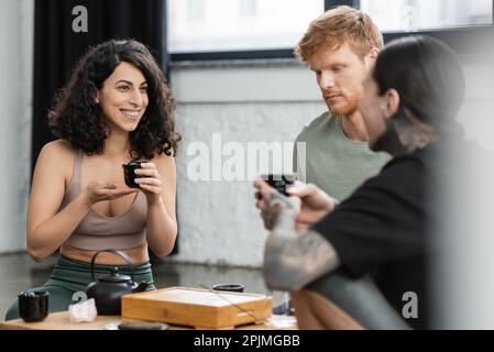 Glückliche Frau aus dem Nahen Osten, die eine Teezeremonie mit Leuten im Yoga-Studio hat, Stock Image Stockfoto
