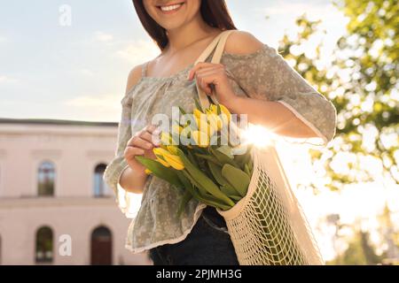 Junge Frau mit einem Strauß gelber Tulpen auf der Straße der Stadt, Nahaufnahme Stockfoto