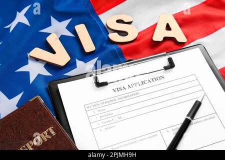 Word Visum, Antragsformular und Reisepass unter amerikanischer Flagge. Einwanderung in die USA Stockfoto