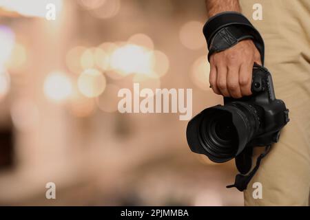 Professioneller Fotograf mit moderner Kamera und verschwommenem Hintergrund, Platz für Text Stockfoto