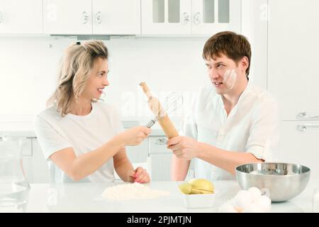 Mann und Frau streiten sich beim Kochen in der Küche. Komische und fröhliche Konfrontation zwischen Mann und Frau in der Küche. Hintergrund... Stockfoto