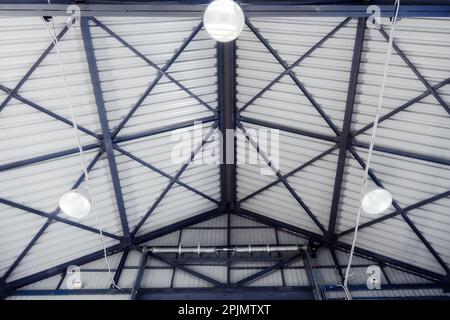 Dach des Industriehangars oder Lagerhauses mit Decken- und Beleuchtungslampen aus Metall. Innenansicht... Stockfoto