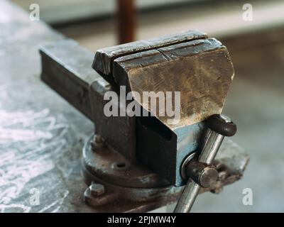 Werkbank aus Metall mit Viskel zum Spannen von Teilen. Ansicht des Arbeitsplatzes in der Werkstatt. Ordnung und Sauberkeit am Arbeitsplatz. Stockfoto