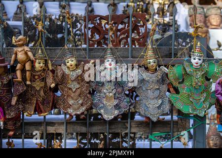 Bunte Marionetten in einem Touristenstand auf dem Straßenmarkt in Burma. Souvenir-Artikel zum Verkauf in Myanmar. Handgemachte Puppen hängen auf Display Store Stockfoto