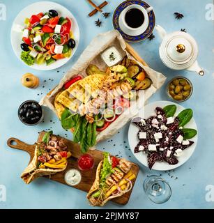 Griechisches Essen auf blauem Hintergrund. Gyros, griechischer Salat, Souvlaki – Auswahl an griechischen Gerichten Stockfoto