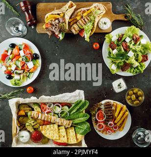 Griechisches Essen mit Kopierbereich in der Mitte, auf dunklem Hintergrund. Gyros, griechischer Salat, Souvlaki, gegrilltes Gemüse - Auswahl an griechischer Küche Stockfoto