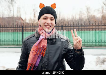 Ein fröhlicher junger Mann mit Tigerohren auf dem Kopf lacht, während er in die Kamera schaut. Zur Feier von Maslenitsa. 22. Februar 2015, Kolomna, Moskau reg Stockfoto