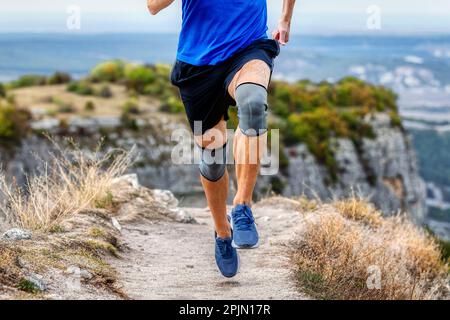 Beinläufer in Knieschützern auf Bergwanderwegen, Knieschutzmanschette nach Verletzung der Stabilisierungsbeine Stockfoto