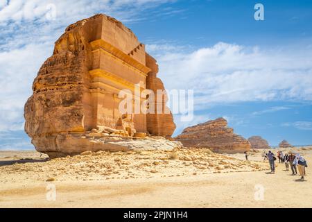 Eine Gruppe von Touristen vor dem Grab von Lihyan, Sohn von Kuza, der in einen Felsen in der Wüste geschnitzt wurde, Mada'in Salih, Hegra, Saudi-Arabien Stockfoto