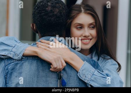 Nahaufnahme eines jungen Paares, das Händchen hält und einen neuen Hausschlüssel. Hypotheken- und Immobilienkonzept Stockfoto