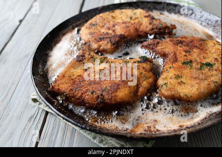 Panierte Schweinekoteletts aus Parmesan in einer heißen Bratpfanne Stockfoto