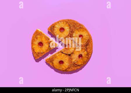 Draufsicht mit einem Ananaskuchen-Minimalist auf einem lila Tisch. Hausgemachter Upside-down-Kuchen mit Ananasringen. Stockfoto