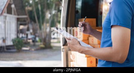 Der Zusteller unterzeichnet die Checkliste auf dem Klemmbrett. Männlicher Kurier, der auf das Klemmbrett schreibt und den Barcode scannt. Der reife Mann aktualisiert die Checkliste der Entbindung im Lieferwagen Stockfoto