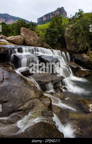 Kleiner Wasserfall, bekannt als Mahai-Kaskaden, mit dem Drakensberg-Gebirge im Hintergrund Stockfoto