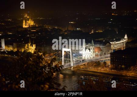 Blick aus dem Nachtwinkel auf die Stadtgemeindekirche, die Elisabethbrücke und St. Stephans Basilika in der Ferne vom Gellert-Hügel in Budapest, Ungarn. Stockfoto