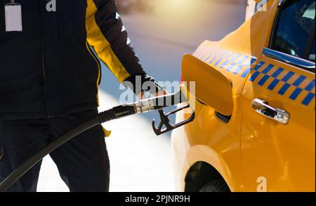 Taxi an der Tankstelle, das mit Benzin auf der Türkei betankt wird. Der Fahrer nimmt die Hände, betankt und pumpt das Benzin an der Tankstelle mit. Stockfoto