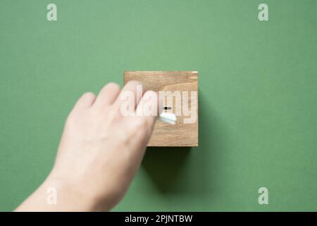 Hand legt hölzerne Stimmzettel auf grünen Hintergrund. Draufsicht Stockfoto