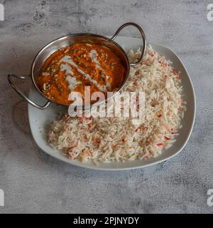 Indische Dishe kulinarisches Still Life. Butterhähnchen serviert mit Reis auf einem Teller Stockfoto