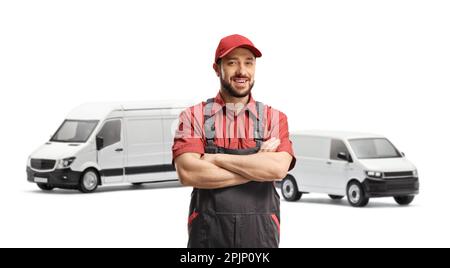 Männlicher Arbeiter in Uniform mit gekreuzten Armen und zwei weißen Vans im Rücken isoliert auf weißem Hintergrund Stockfoto