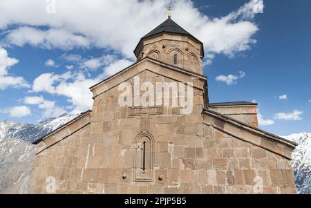 Gergeti Trinity Church im Außenbereich unter bewölktem Himmel. Die Kirche befindet sich am rechten Ufer des Flusses Chkheri unter dem Berg Kasbek in Georgia Stockfoto