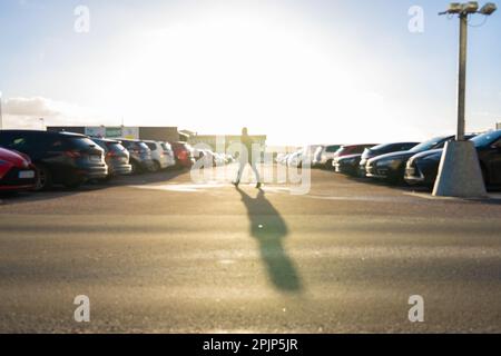 Unscharfes Bild einer Person, die über einen Parkplatz geht Stockfoto