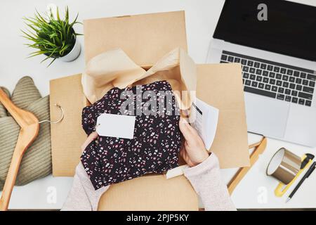 Geschäftsinhaber, der Online-Bestellungen bis zur Auslieferung an den Kunden verpackt. Vorbereiten der Paketbox mit Kleidungsstücken aus dem Online-Shop Stockfoto