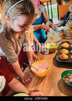 Gruppe von Kindern, die Cupcakes backen, Zutaten zubereiten, Toppings, Streuseln zum Dekorieren von Keksen. Kinder lernen kochen, arbeiten zusammen Stockfoto