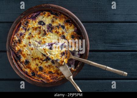 Quark-Auflauf gebacken mit Heidelbeere, Nahaufnahme. Kasserolle mit frischen Beeren auf schwarzem Tisch. Draufsicht Stockfoto