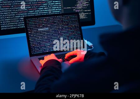 Mann, der Computer und Programmierung verwendet, um Code zu brechen. Cyber-Sicherheitsbedrohung. Internet- und Netzwerksicherheit. Diebstahl privater Informationen. Person, die te Stockfoto