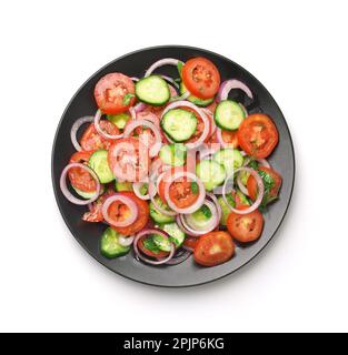 Draufsicht auf frischen Tomaten-Gurken-Gemüsesalat in schwarzer Platte isoliert auf weiß Stockfoto