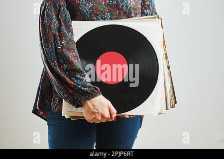 Frau mit Schallplatten. Leidenschaft für Musik. Analoge Musikwiedergabe. Wiedergabe von Musik von einer analogen Festplatte auf einem Plattenspieler. Musik genießen Stockfoto