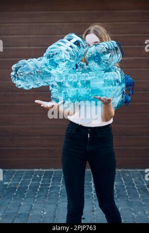 Junge Frau, die leere Plastikwasserflaschen in den Mülleimer wirft. Sammlung von Kunststoffabfällen für das Recycling. Zum Begriff der plastischen Verschmutzung Stockfoto