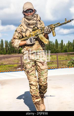 Ein Mädchen mit einem Sturmgewehr, eine starke, entschlossene und fähige Frau. Er hält die Waffe mit Selbstvertrauen und Geschick und ist an einer militärischen Operation beteiligt. In Militärausrüstung gekleidet, für Militär- oder Strafverfolgungszwecke. Stockfoto