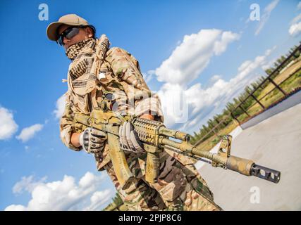 Ein Mädchen mit einem Sturmgewehr, eine starke, entschlossene und fähige Frau. Er hält die Waffe mit Selbstvertrauen und Geschick und ist an einer militärischen Operation beteiligt. In Militärausrüstung gekleidet, für Militär- oder Strafverfolgungszwecke. Stockfoto